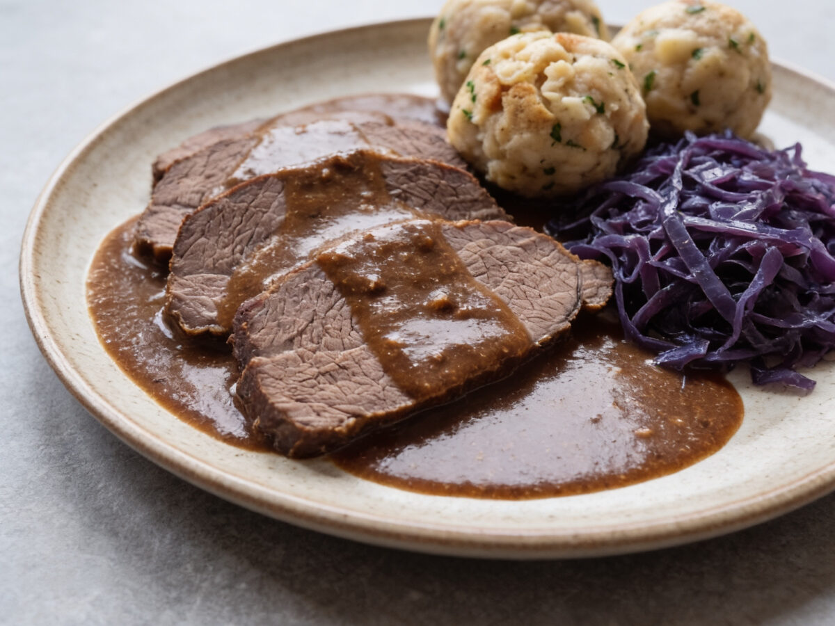 Bayern | Bayerischer Sauerbraten | Zartes Rindfleisch in säuerlicher Lebkuchensoße mit Knödeln und Rotkohl